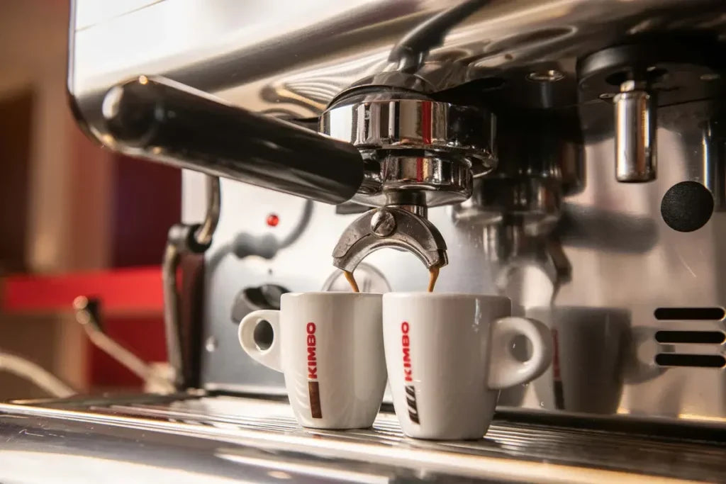 Zwei Kimbo Tassen unter einer Espresso-Siebträgermaschine